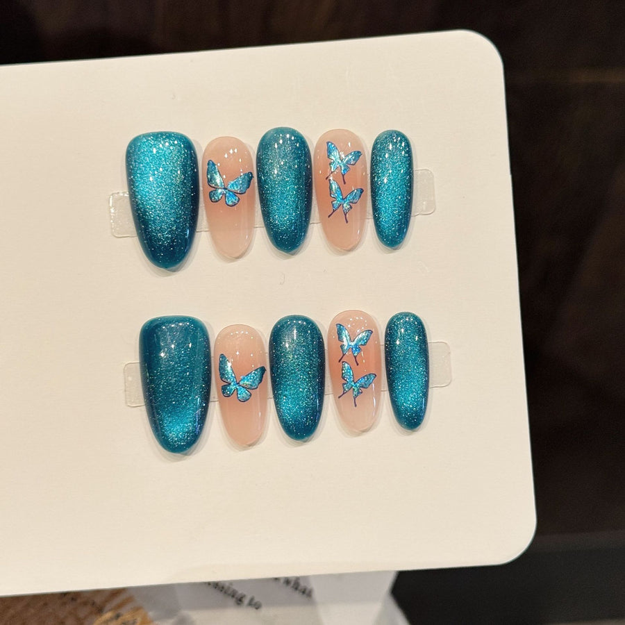 Ongles press-on bleu pailleté et nude, motif papillon, frais et élégants