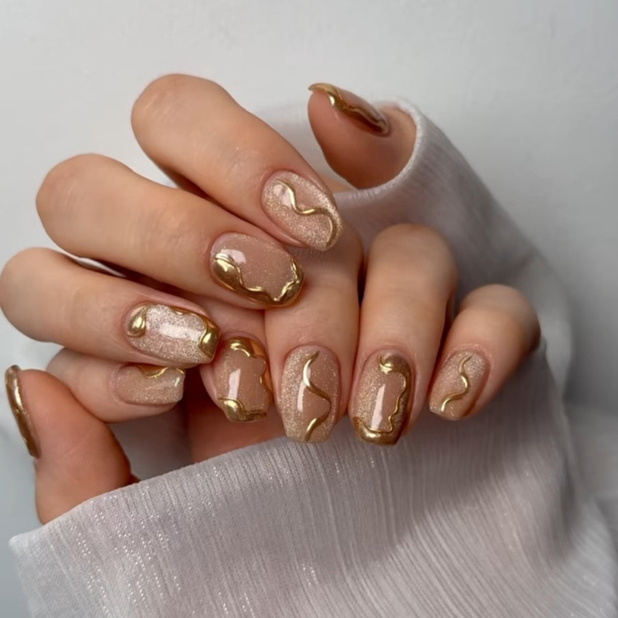 Ongles nude à tourbillons dorés — finition brillante scintillante