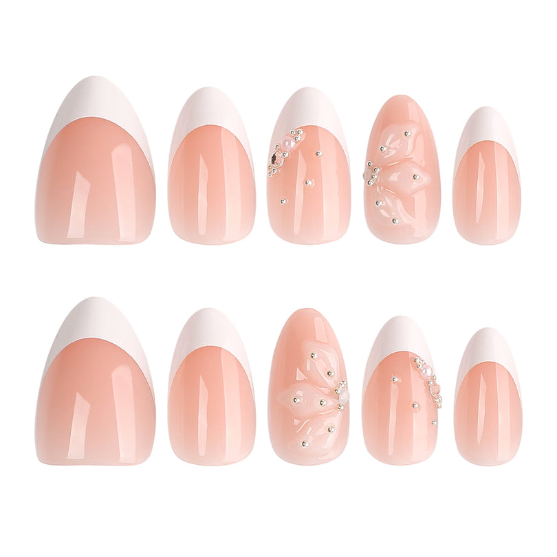 Two rows of nude French almond press-on nails with white tips, 3D flowers and rhinestones.