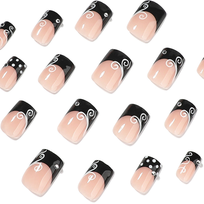 Close-up of black french tip square press-on nails with white swirls and small rhinestones