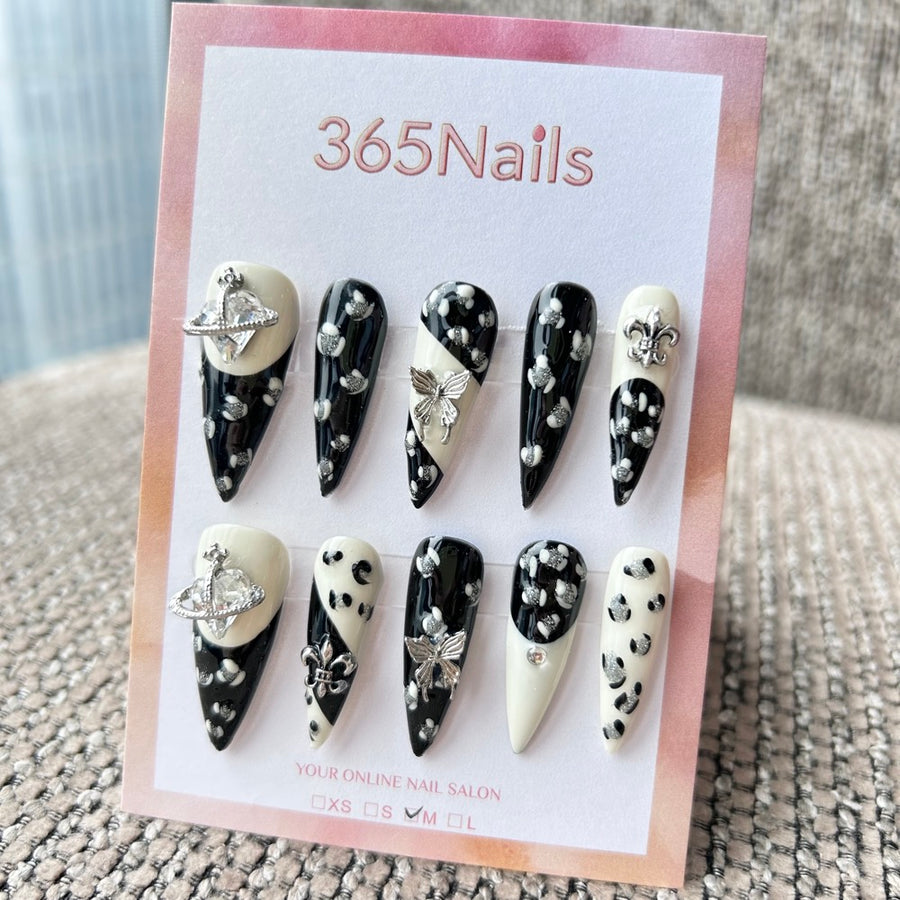 Femme Fatale: "Rebelle Saturne" – léopard monochrome noir et blanc avec orbe planétaire argentée et breloques papillon, ongles press-on longs forme stiletto