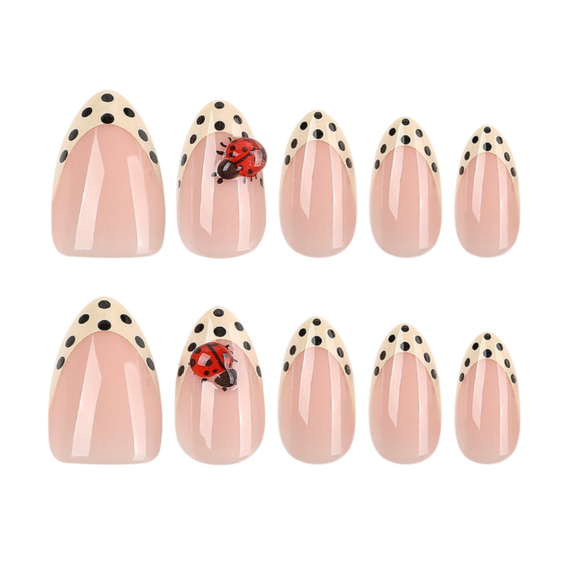 Flat lay of ten glossy pink almond press-on nails with cream dotted french tips and two 3D ladybug accent nails