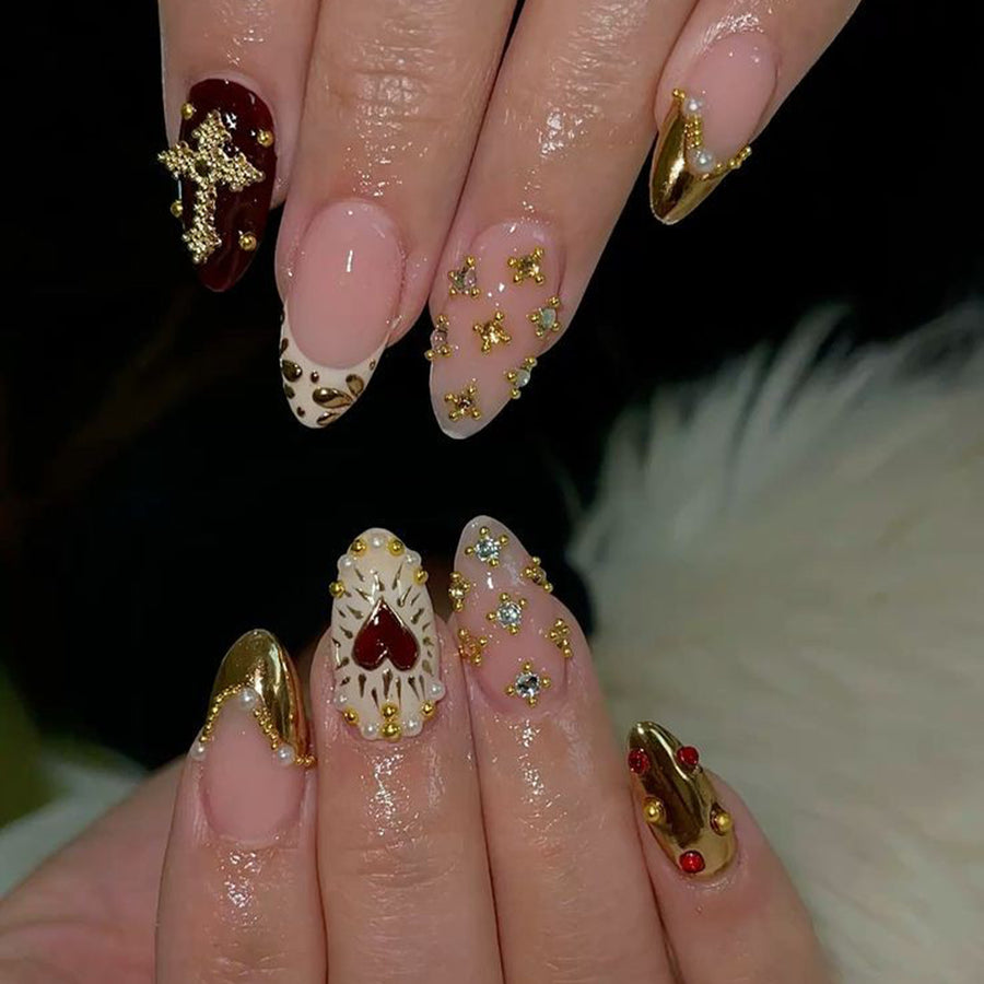Hand wearing the ornate press-on nail set with heart and gold charms