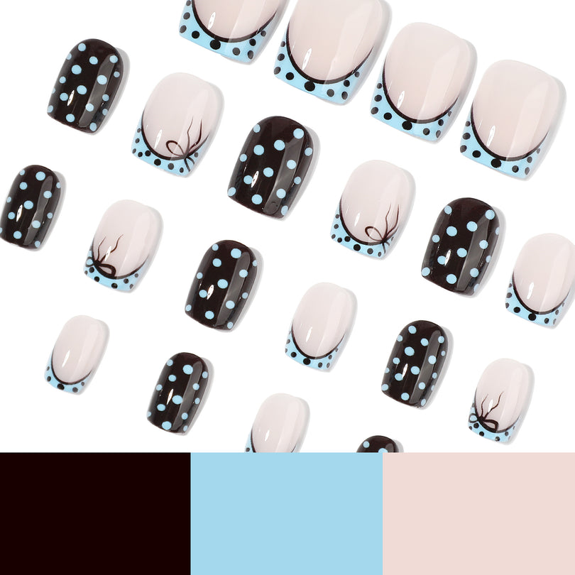 Scattered black and nude square press-on nails with blue polka dots and a color swatch strip