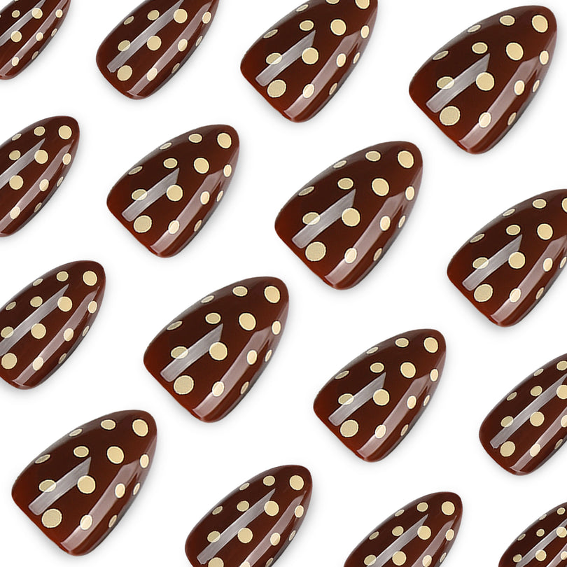 Close-up of glossy brown press-on nails with cream dots