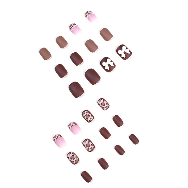 Scattered brown, pink and leopard print press-on nails laid out on white background