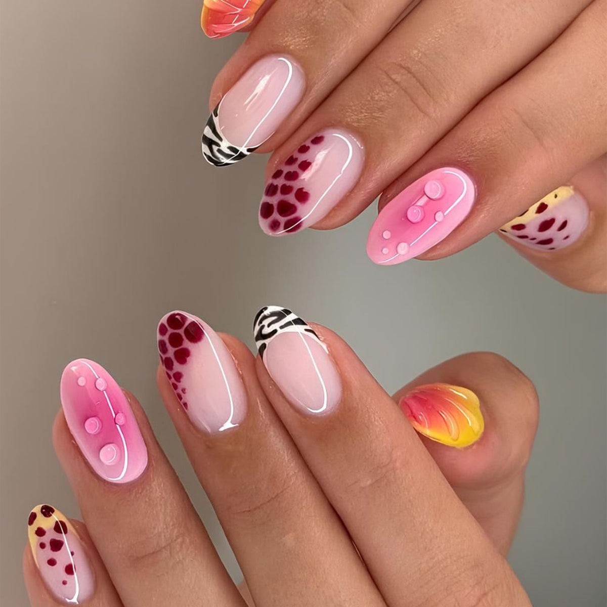 Hands displaying press-on nails with leopard, zebra, and 3D designs