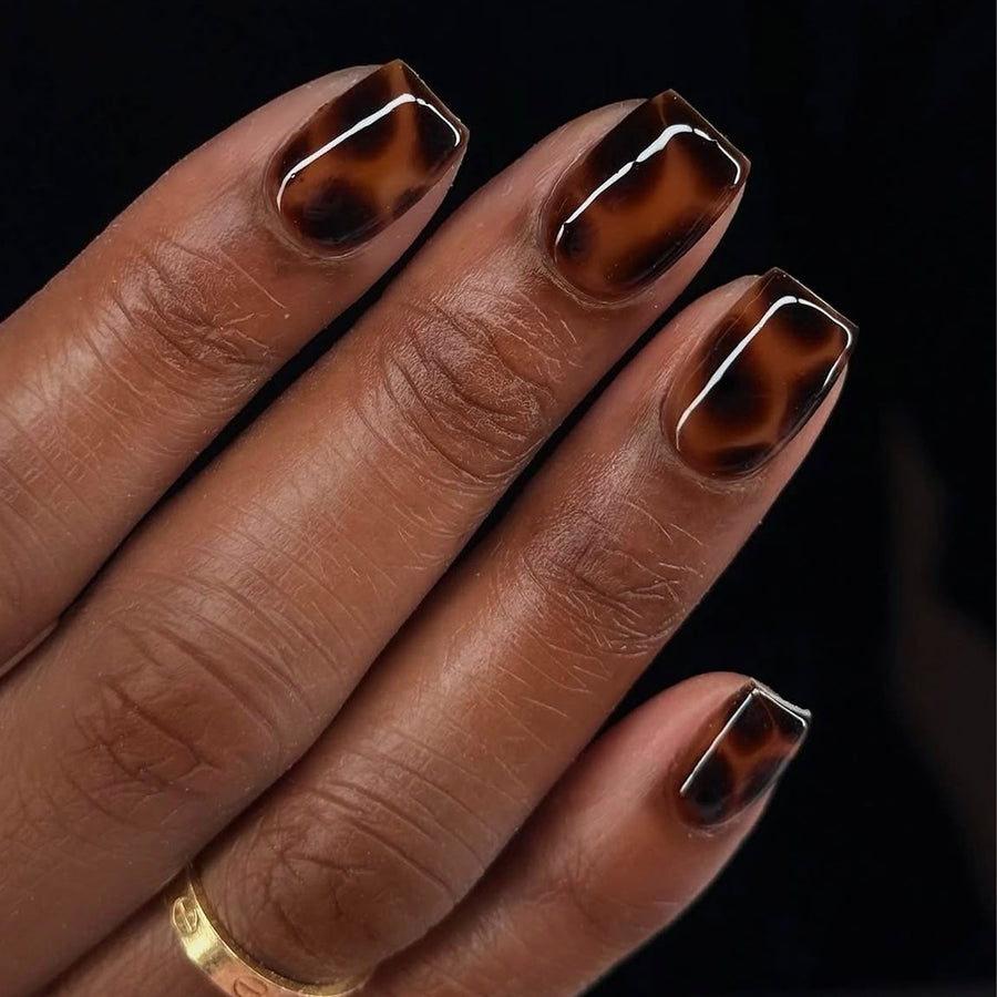Hand wearing glossy brown tortoiseshell square press-on nails