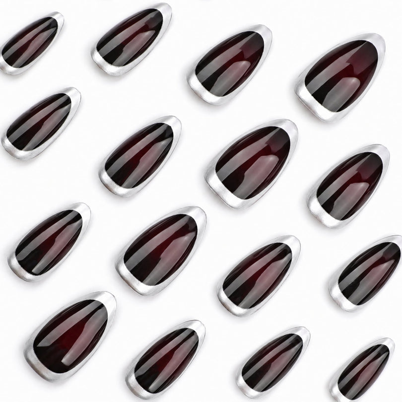 Many burgundy almond nail pieces with silver borders displayed on white background